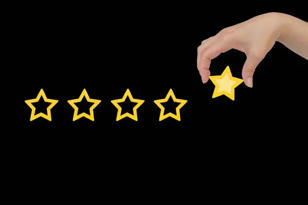 Woman\'s hand put the stars to complete five stars. Customer satisfaction concept. copy space and the background of the blackboard. giving a five star rating. Service rating, satisfaction concept.