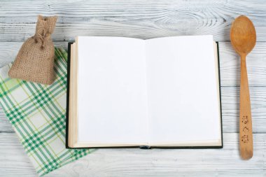 Tarifi ahşap arka plan, kaşık, oklava, damalı masa örtüsü üzerinde yemek boş kitap.