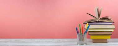 Kitap istifleme. Açık kitap, ahşap masa ve mavi arka plan üzerine ciltli kitaplar. Okula dönelim. Uzayı metin için kopyala. Pankart