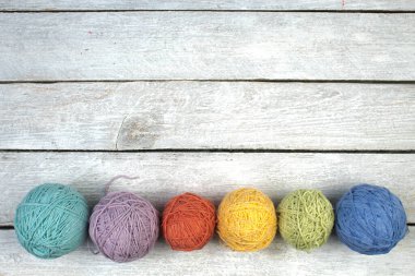 Beyaz ahşap bir masada renkli iplik. Örgü örmek için yün derileri. Ahşap arka planda el yapımı örgü örmek için farklı renkte yün toplar ve reklam için kopya alanı