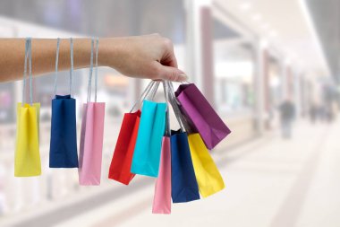 Alışveriş merkezi arka plan üzerinde renkli kağıt torba tutarak kırpma el