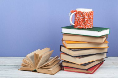 Kitap istifleme. Açık kitap, ahşap masa ve mavi arka plan üzerine ciltli kitaplar. Okula dönelim. Metin için alanı kopyala
