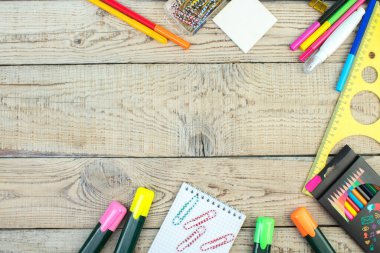 Okula dönelim. Makas, kalem, ataç, not defteri, keçeli kalem, cetvel. Okul malzemeleri ahşap bir masada. Kopyalama alanı olan üst görünüm