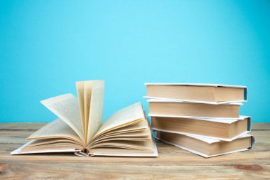 Açık bir kitap, mavi arka planda kitaplar. Okula dönelim. Eğitim. Metin için alanı kopyala