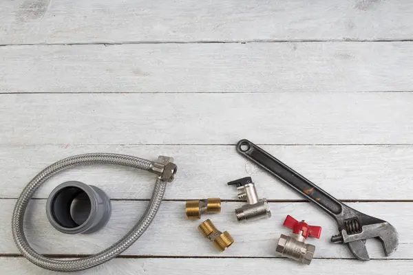 Teçhizatlar, boru, valfler, su için plastik boru ahşap arka planda ayarlanabilir ingiliz anahtarı. Üst Manzara. Metin için alanı kopyala