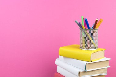 Kitaplar istifleniyor. Tahta masadaki kitaplar ve pembe arka plan. Okula dönelim. Reklam metni için alanı kopyala