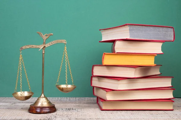 Law concept - Open law book, Judge\'s gavel, scales, Themis statue on table in a courtroom or law enforcement office. Wooden table, green background.