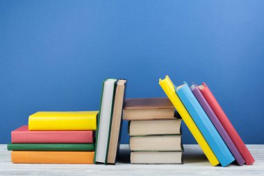 Kitap istifleme. Açık kitap, ahşap masa ve mavi arka plan üzerine ciltli kitaplar. Okula dönelim. Metin için alanı kopyala