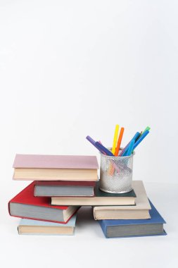 Açık bir kitap, ahşap masa üzerinde ciltli renkli kitaplar, beyaz arka plan. Okula dönelim. Uzayı metin için kopyala. Eğitim sektörü kavramı