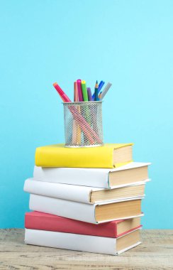 Kitaplar istifleniyor. Kitaplar ahşap masada ve mavi arka planda. Okula dönelim. Reklam metni için alanı kopyala