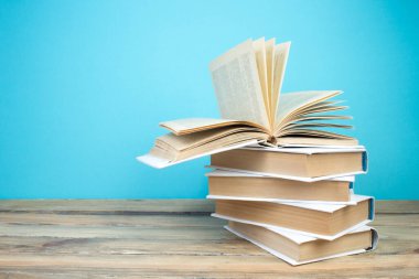 Açık bir kitap, mavi arka planda kitaplar. Okula dönelim. Eğitim. Metin için alanı kopyala