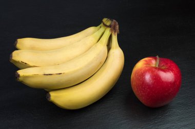 Meyveler. Siyah arkaplanda muz, elma, portakal.