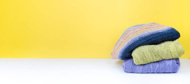 Yünlü yün kazaklar. Bir demet örülmüş kış, sarı arka planda sonbahar kıyafetleri, kazaklar, örgü giysiler, yazı için yer. Pankart