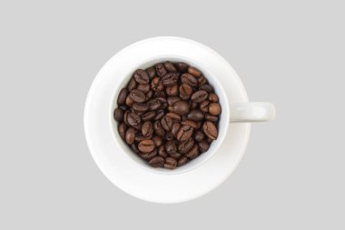 Gri arka planda izole edilmiş kahve taneleri olan bir fincan. en üstteki görünüm