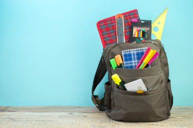 Sırt çantasında farklı renkte kırtasiye malzemeleri var. Açık mavi arkaplan. Okula geri dön.