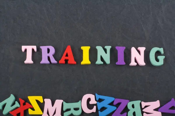 TRAINING word on black board background composed from colorful abc alphabet block wooden letters, copy space for ad text. Learning english concept