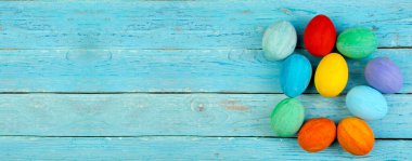 Mutlu Paskalyalar. Ahşap arka planda renkli, parlak paskalya yumurtaları. Metin için boşluk kopyala, Banner
