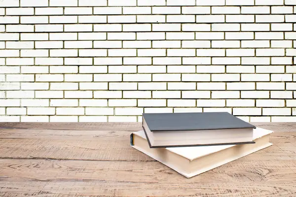 open book. Composition with hardback books, fanned pages on wooden deck table and Brick wall background. Books stacking. Back to school. Copy Space. Education background