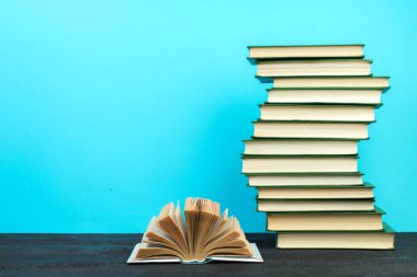 Açık bir kitap, ahşap masadaki ciltli kitaplar, mavi bir arka plan. Okula dönelim. Uzayı metin için kopyala. Eğitim geçmişi