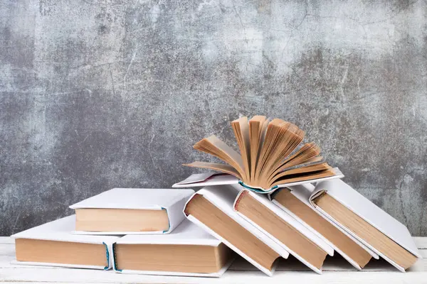 Açık kitaplar, ahşap masada ciltli renkli kitaplar. gri beton arka plan. Okula dönelim. Uzayı metin için kopyala. Eğitim sektörü kavramı