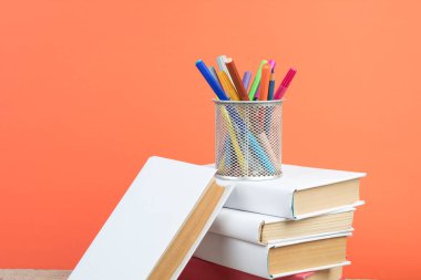 Kitaplar istifleniyor. Tahta masa ve turuncu arka plandaki kitaplar. Okula dönelim. Reklam metni için alanı kopyala