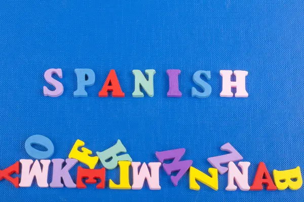 SPANISH word on blue background composed from colorful abc alphabet block wooden letters, copy space for ad text. Learning english concept
