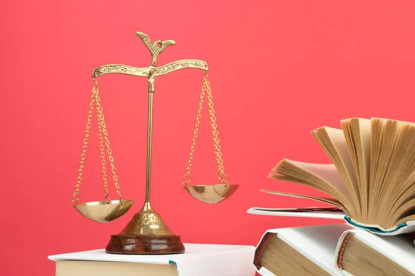 Law concept - Open law book, Judge\'s gavel, scales, Themis statue on table in a courtroom or law enforcement office. Wooden table, red background