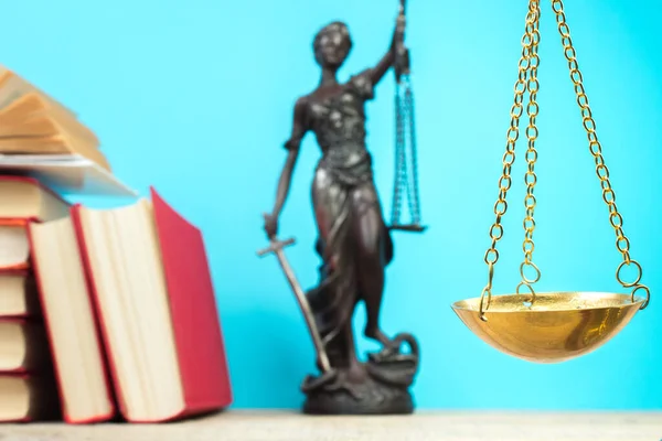 Hukuk konsepti - açık hukuk kitabı, yargıç tokmağı, teraziler, mahkeme salonundaki ya da kolluk kuvvetlerindeki heykel. Ahşap masa, mavi arkaplan.