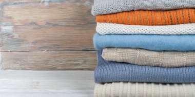 Örgü yün kazaklar. Ahşap arka planda örülmüş kış kıyafetleri, kazaklar, örgü giysileri, metin için yer.