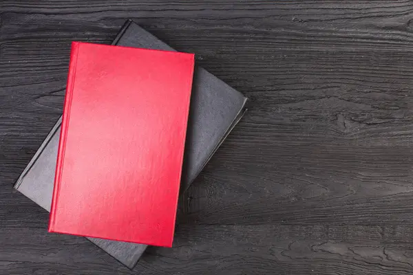 Red, black books on a black wooden desk. top view