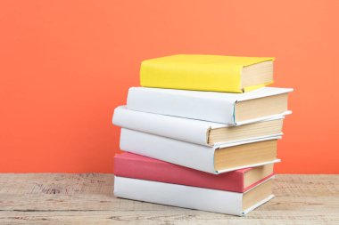 Kitaplar istifleniyor. Tahta masa ve turuncu arka plandaki kitaplar. Okula dönelim. Reklam metni için alanı kopyala