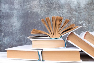 Açık kitaplar, ahşap masada ciltli renkli kitaplar. gri beton arka plan. Okula dönelim. Uzayı metin için kopyala. Eğitim sektörü kavramı