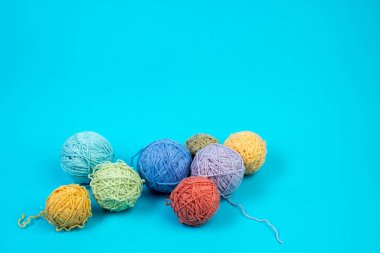 Mavi arka planda renkli iplik. Örgü örmek için yün derileri. Ahşap arka planda el yapımı örgü örmek için farklı renkte yün toplar ve reklam için kopya alanı