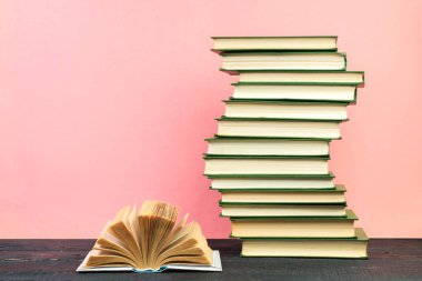 Açık bir kitap, ahşap masa üzerinde, pembe arka planda ciltli kitaplar. Okula dönelim. Uzayı metin için kopyala. Eğitim geçmişi