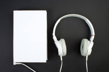 Kulaklık, cep telefonu, idiobook, siyah arka planda kahve fincanı. Boş zaman ve öğrenme kavramı, hobi. Müzik dinlemek, edebiyat. Kopyalama alanı olan üst görünüm