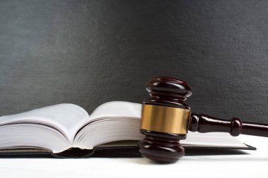 Hukuk kavramı - Beyaz masa üzerinde izole bir mahkeme veya kolluk bürosunda masada ahşap bir hakim tokmak ile açık hukuk kitabı. Metin için alan kopyalama.
