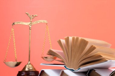 Hukuk konsepti - açık hukuk kitabı, yargıç tokmağı, teraziler, mahkeme salonundaki ya da kolluk kuvvetlerindeki heykel. Tahta masa, turuncu arka plan.