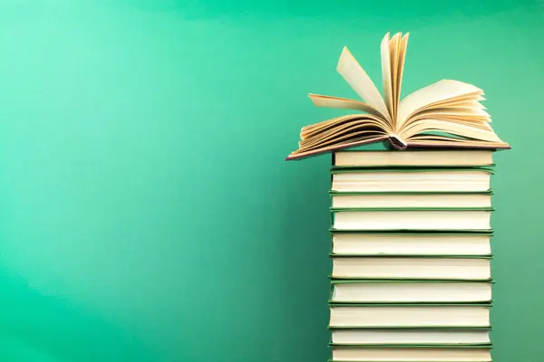 Açık bir kitap, ahşap masa üzerindeki ciltli kitaplar, yeşil bir arka plan. Okula dönelim. Uzayı metin için kopyala. Eğitim geçmişi