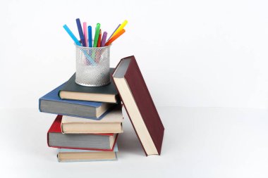 Açık kitap, ahşap masa, beyaz arka plan üzerinde renkli ciltli kitap. Okula dönüş. Kalem, kalem, bardak. Metin için yer kopyalayın. Eğitim iş kavramı