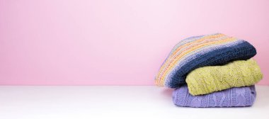 Yünlü yün kazaklar. Kış örgüsü, pembe arka planda sonbahar kıyafetleri, kazaklar, örgü giysiler, yazı için yer. Pankart