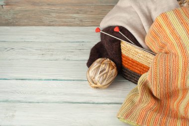 Yün, iğneler ve yün kazak için el yapımı örgü sepeti ahşap masa üzerinde konuşmacı ile Top