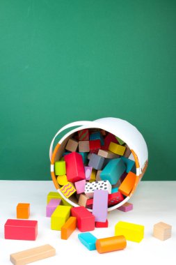 Çocuk oyuncağı, ahşap inşaatçı, yeşil arka planda bir kovadan dökülmüş.