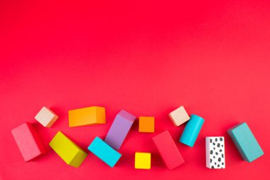 Masadaki renkli ahşap tuğlaların üst görüntüsü. Erken öğrenme. Kırmızı arka planda eğitici oyuncaklar. Çocuğun gelişimi için..
