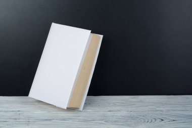 Ahşap masa, siyah tahta arka plan üzerine açık siyah ve beyaz kitaplar. Okula dönüş. Eğitim iş kavramı