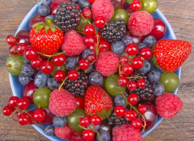 Bir kase rustik ahşap masa üzerinde çeşitli yaz taze çilek. Antioksidan, detoks diyet, organik meyve