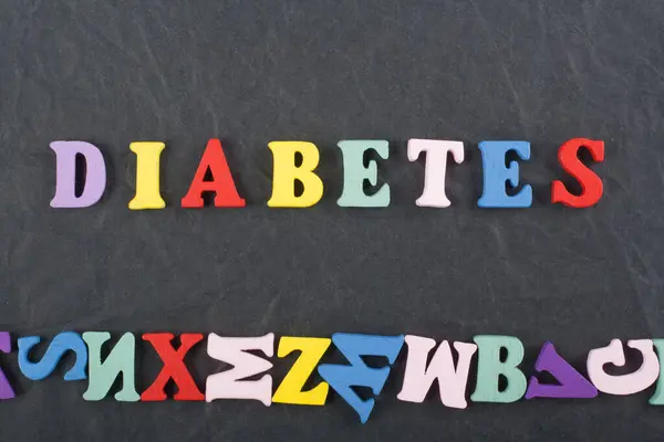 DIABETETES word on black board background composed from colorful abc alphabet block wooden letters, copy space for ad text. Learning english concept