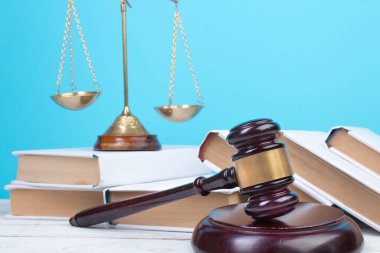 Hukuk konsepti - açık hukuk kitabı, yargıç tokmağı, teraziler, mahkeme salonundaki ya da kolluk kuvvetlerindeki heykel. Ahşap masa, mavi arkaplan