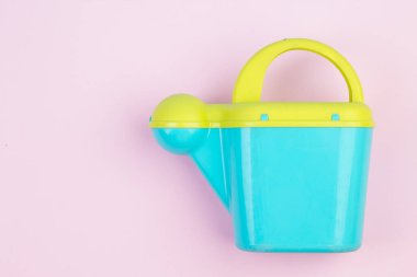 Kum havuzunda ya da bahçede oynamak için çocuk plastik sulama kutusu. Çiçekleri sulamak için renkli sulama kutusu, pembe arka planda vurgulanmış