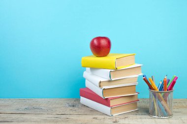 Kitaplar istifleniyor. Kitaplar ahşap masada ve mavi arka planda. Okula dönelim. Reklam metni için alanı kopyala