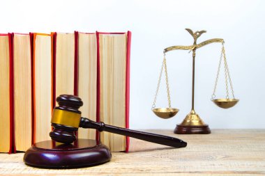 Hukuk konsepti - açık hukuk kitabı, yargıç tokmağı, teraziler, mahkeme salonundaki ya da kolluk kuvvetlerindeki heykel. Tahta masa, beyaz arkaplan.